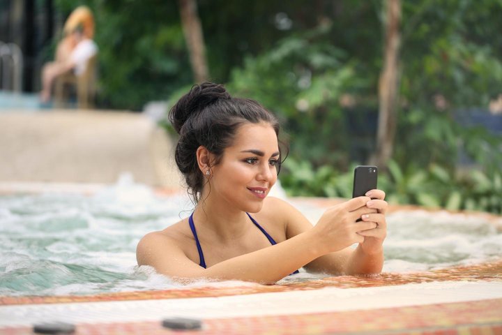 Vrouw in jacuzze met mobiel
